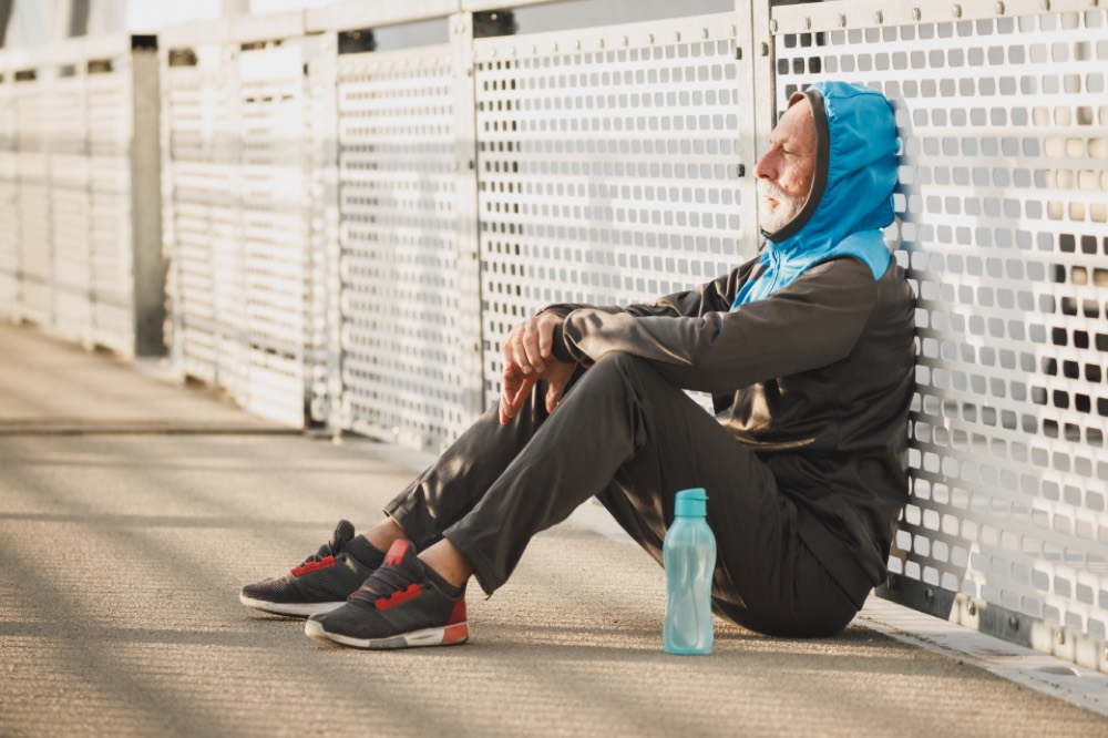 Athlete sitting down to rest against a wall