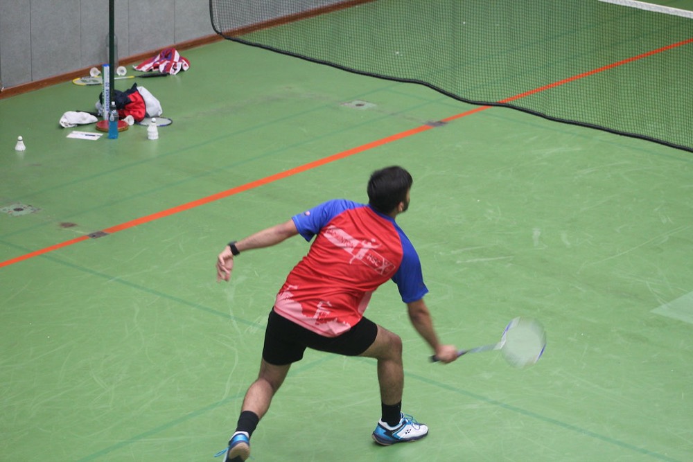 Singles player stretching wide to reach a shuttle