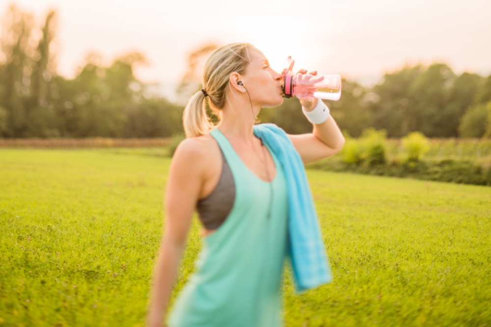 Woman drinking water after exercise outdoors