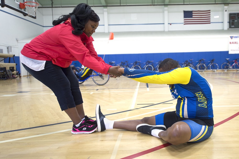 Coach helping a player stretch in a sports hall