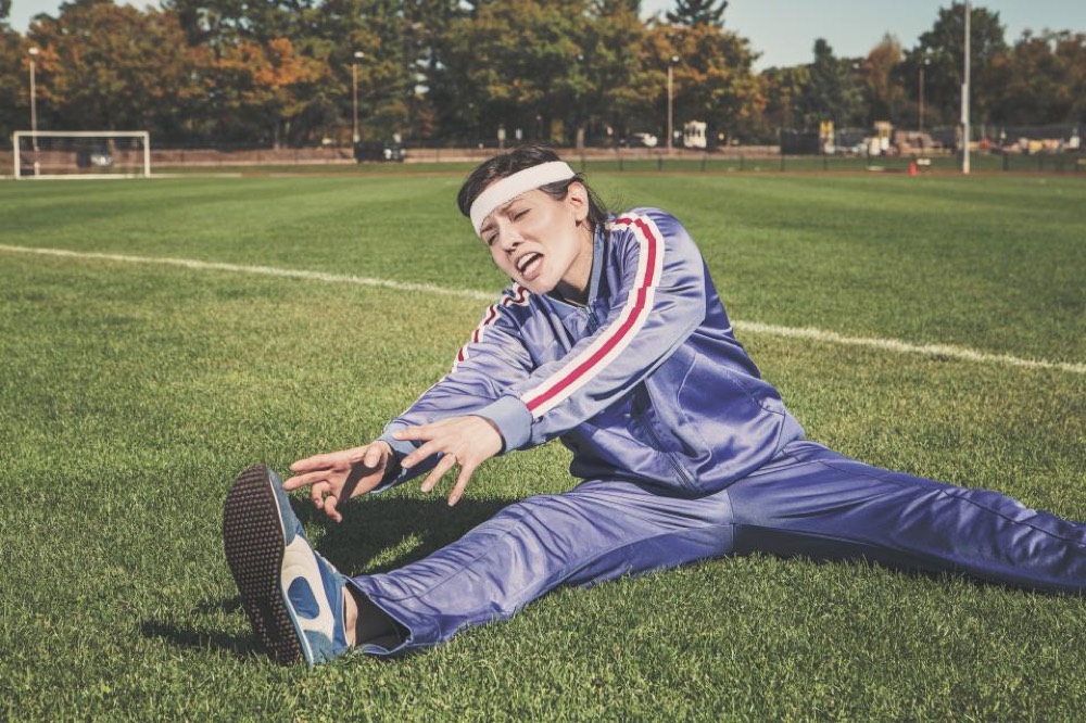 Athlete stretching a sore leg on a sports field