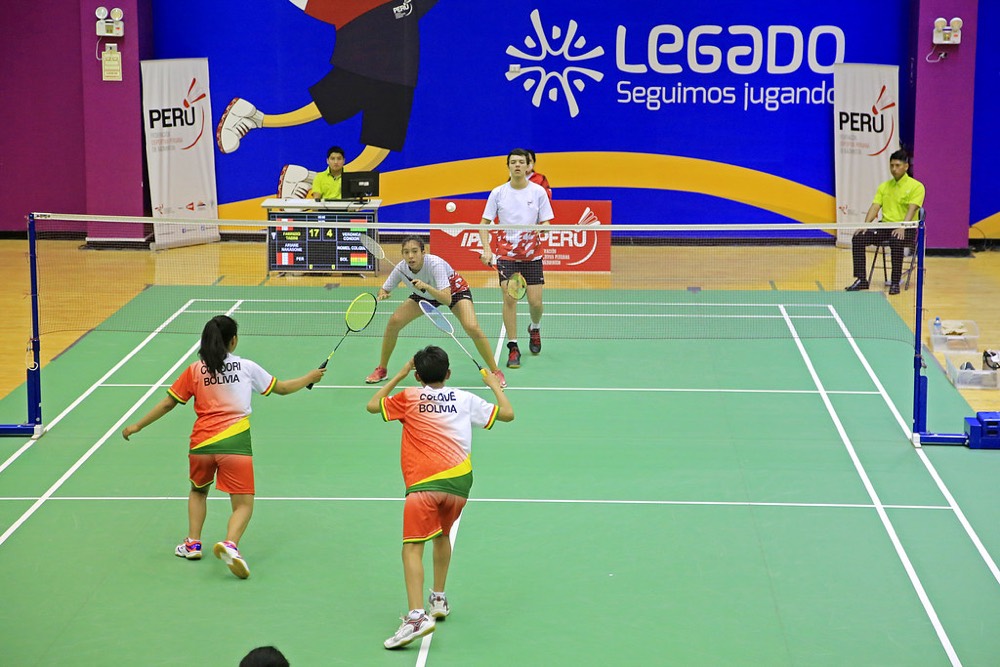 Young players enjoying a doubles game on a green badminton court