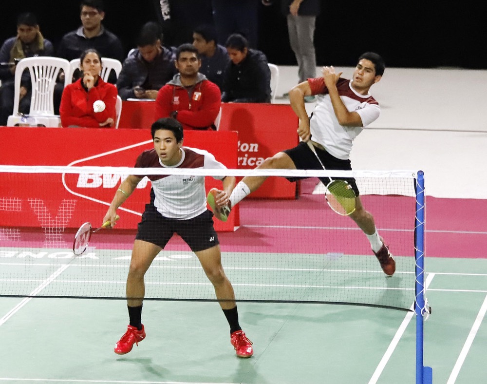 Player attacking the shuttle at the net in a doubles match